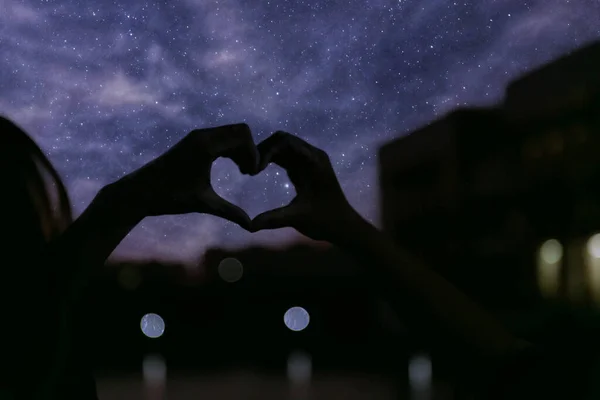 hands holding heart in the hand on the background of the night sky