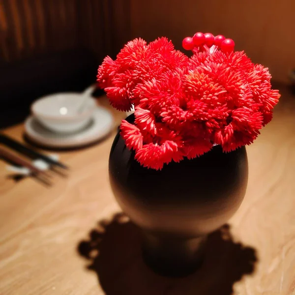 beautiful red flower in a vase on a wooden background