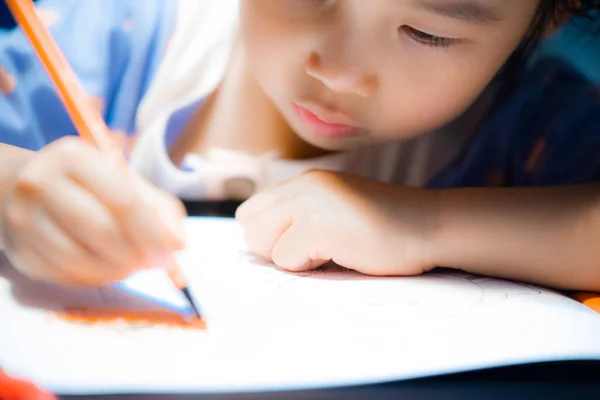 little girl draws a pencil on the table