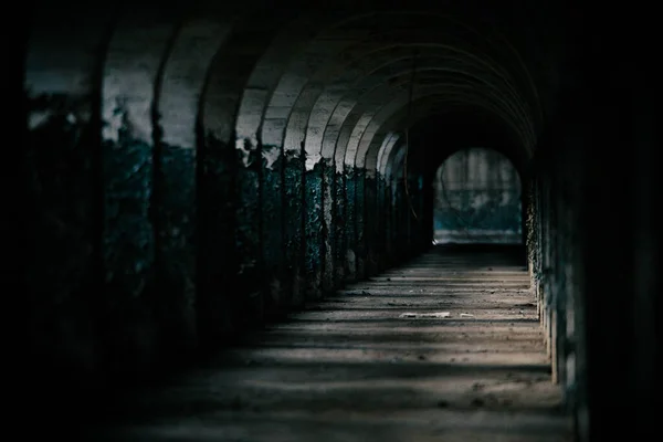 underground tunnel with dark stone and concrete floor.