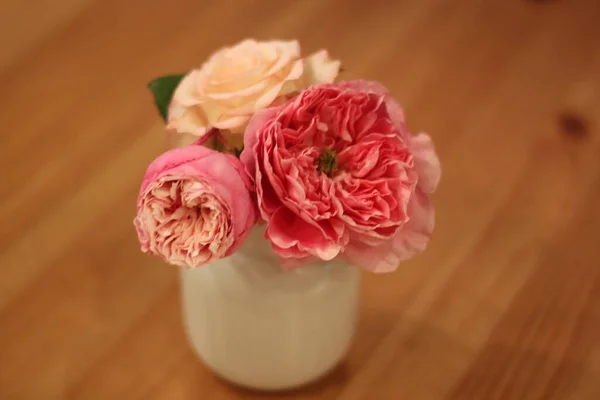 beautiful pink roses in a vase on a wooden background
