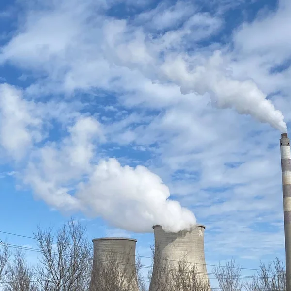 industrial power plant with smoke and blue sky