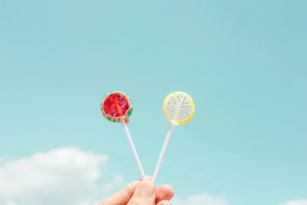 hand holding lollipop with a stick on a blue background