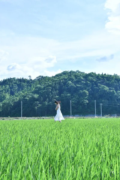 young woman in white dress with a bag of rice in the field