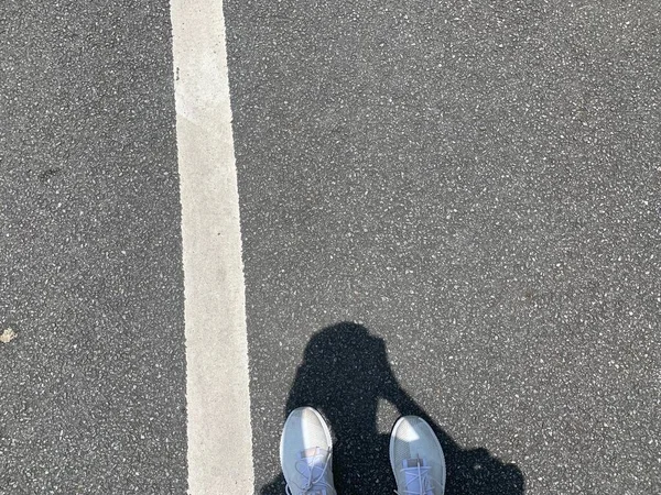 a closeup shot of a person standing on a road with a blurred background