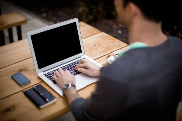 close-up of a man using a laptop and a digital tablet