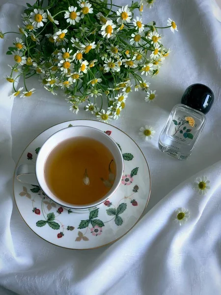 cup of tea with chamomile flowers and a teapot on a white background