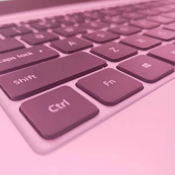 close up of a computer keyboard with a pink background