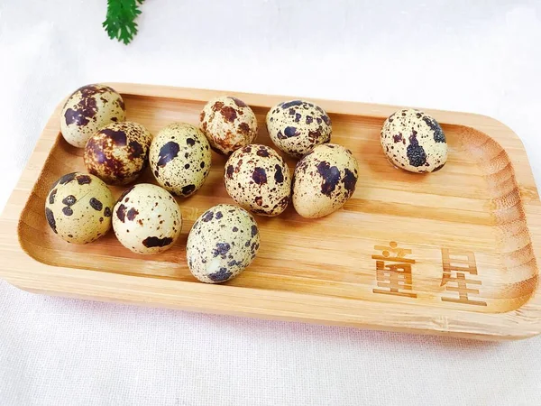 quail eggs in a wooden box on a white background.