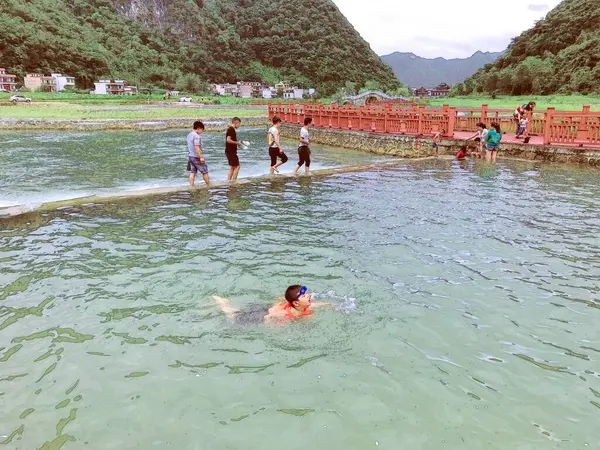 the boy is swimming in the water of the river.