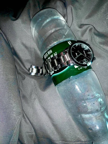 wristwatch with a green cap and a bottle of water on a white background