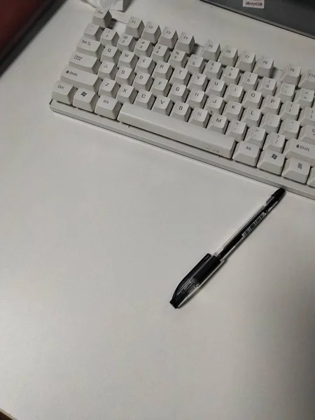 close up of a laptop keyboard with a pen and a computer mouse on a white background