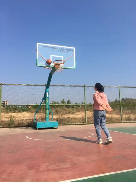 young woman with basketball hoop on the beach