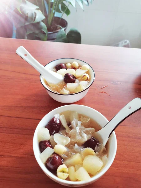 a bowl of white rice with a spoon and a cup of coffee on a wooden table