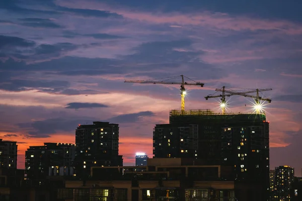 construction cranes and building under sunset sky