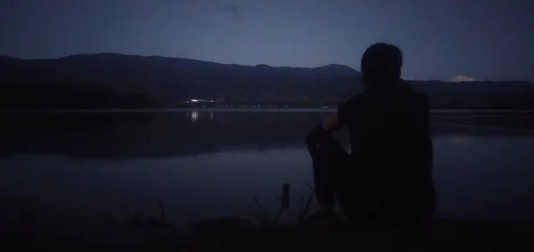 silhouette of a man sitting on the lake