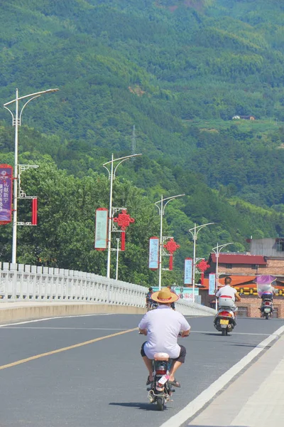 a man in a green t-shirt riding a bicycle on the road