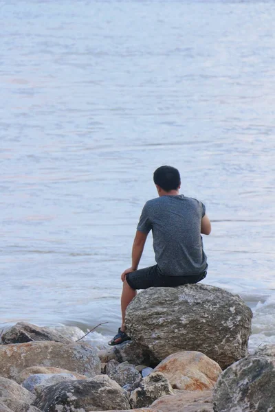 stock image man sitting on the rocks on the sea