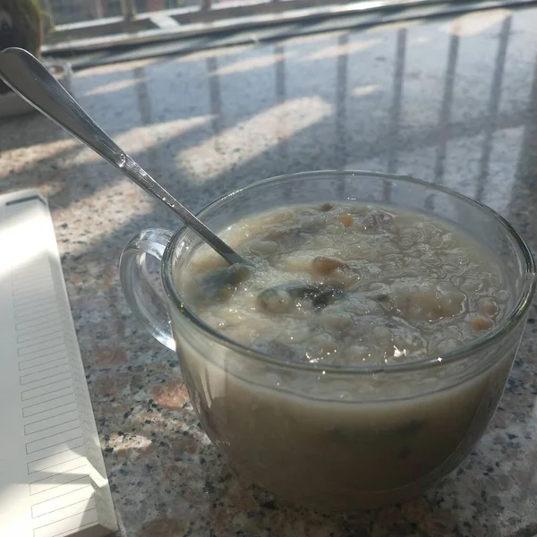 a closeup shot of a glass of milk soup with a spoon