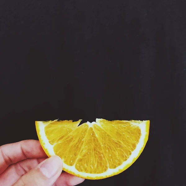 hand holding lemon slices on black background