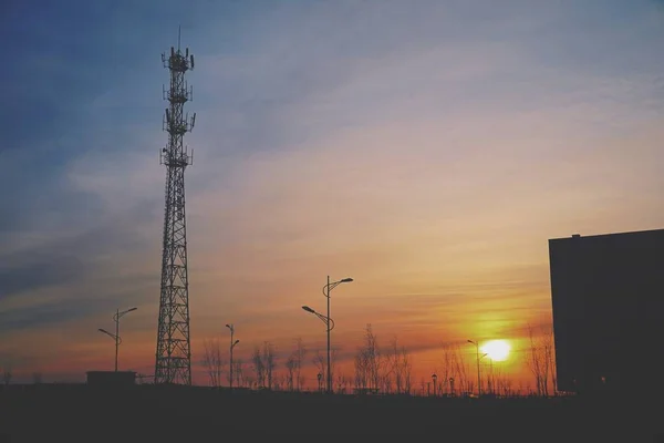 high-voltage tower with antennas and sunset