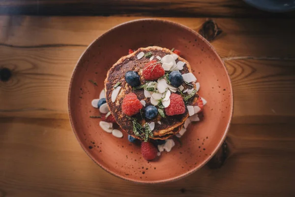 chocolate pancakes with blueberries and raspberries on a wooden background