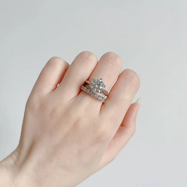 hand holding a diamond ring on a white background