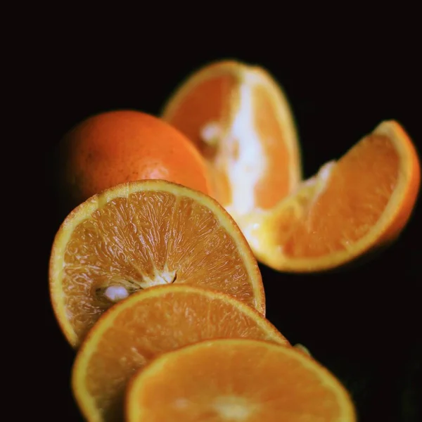 fresh orange and sliced oranges on black background