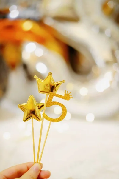 christmas decoration. hand holding a star of white and golden stars on a background of a bright yellow lights