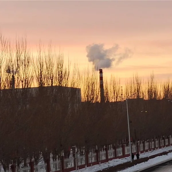 industrial landscape with a chimney and a red smoke