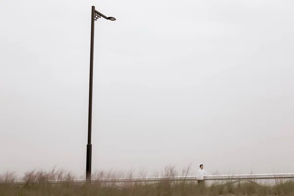 a vertical shot of a wind turbine on a background of a lake