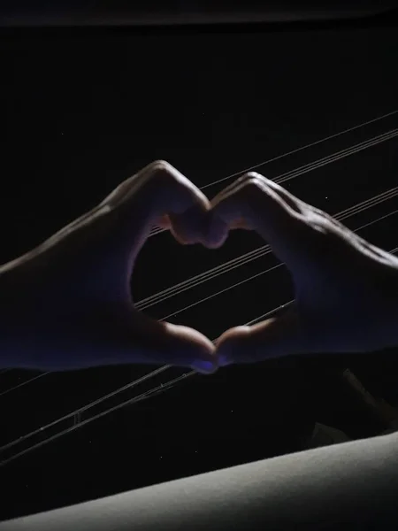 hands holding a book with a heart on a black background