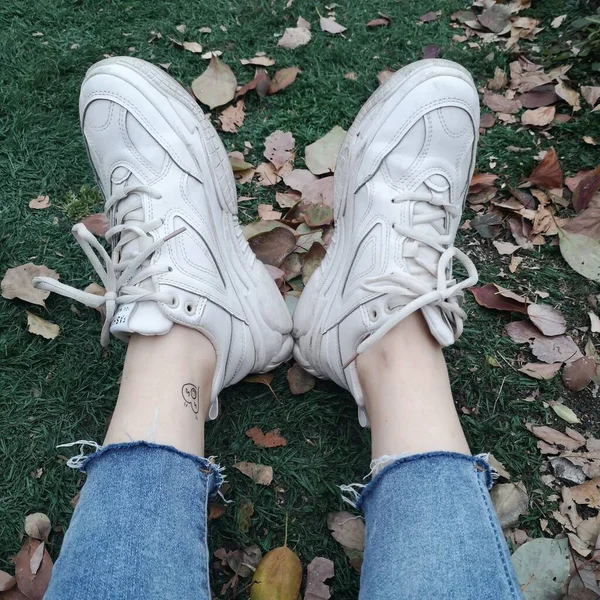 feet of a woman lying on the ground and holding a green grass