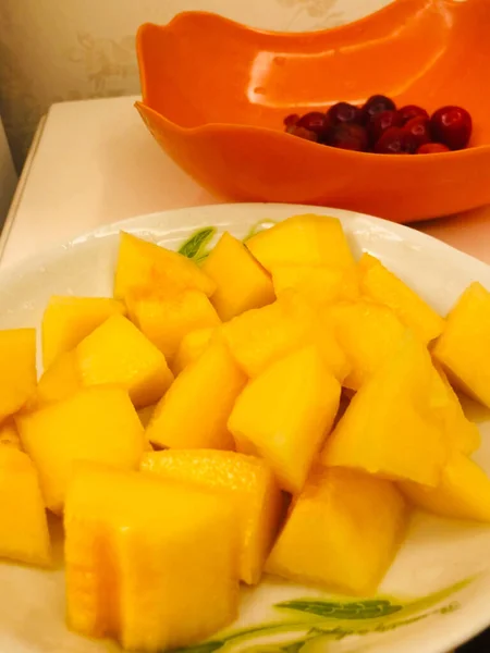 fresh yellow mango slices on a white plate