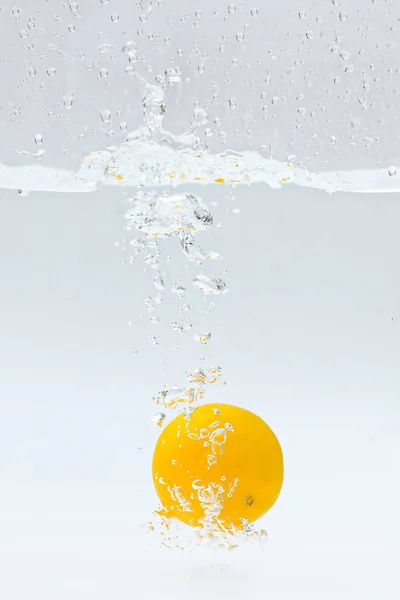 yellow lemon splashing into water splash on white background