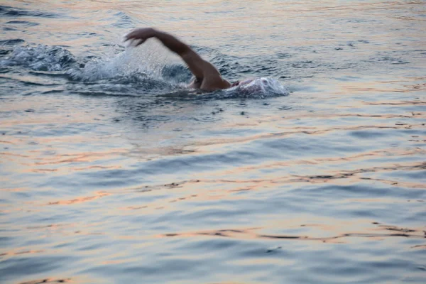 young man in a blue cap is swimming in the water