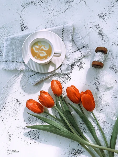 cup of coffee and tulips on white wooden background