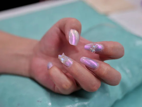 close up of a female hand with a nail polish on a blue background