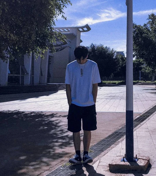 man in a blue t-shirt and a white sweatshirt on the street