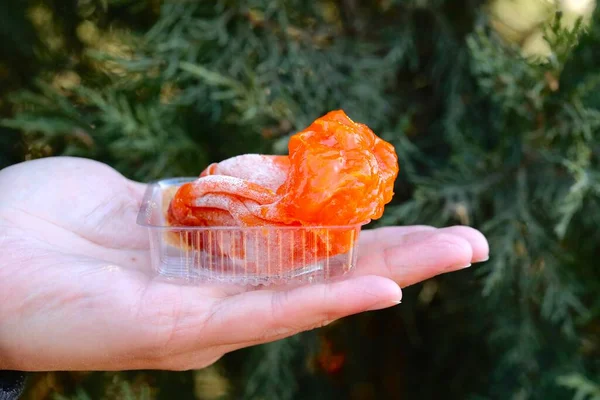 hand holding a red tangerine in the hands of a woman