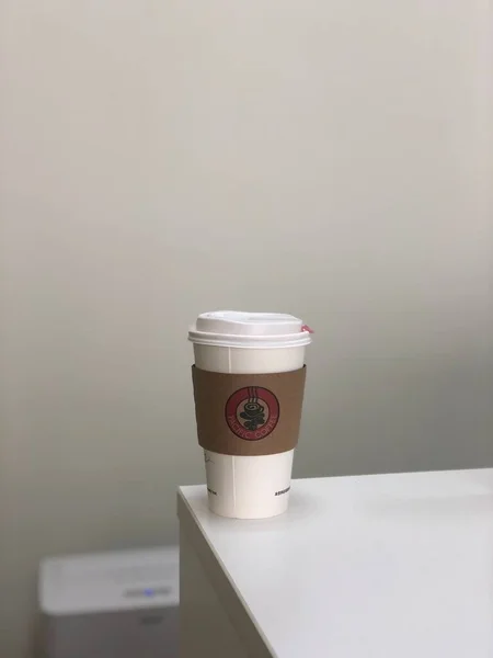 white paper cup with coffee beans on the table