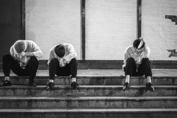black and white photo of young people sitting on stairs and talking on mobile phone