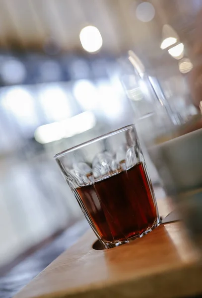 glass of whiskey with a cup of coffee on a wooden table