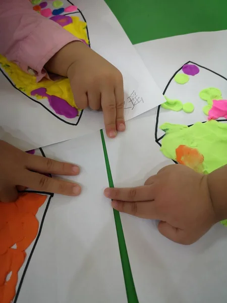 little girl draws a paper with a drawing of a child