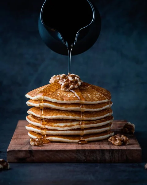 stack of pancakes with honey and nuts on a dark background