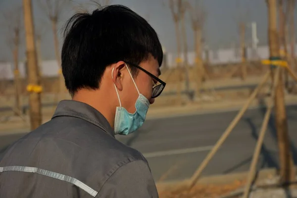 man in a protective mask and glasses is smoking a cigarette.