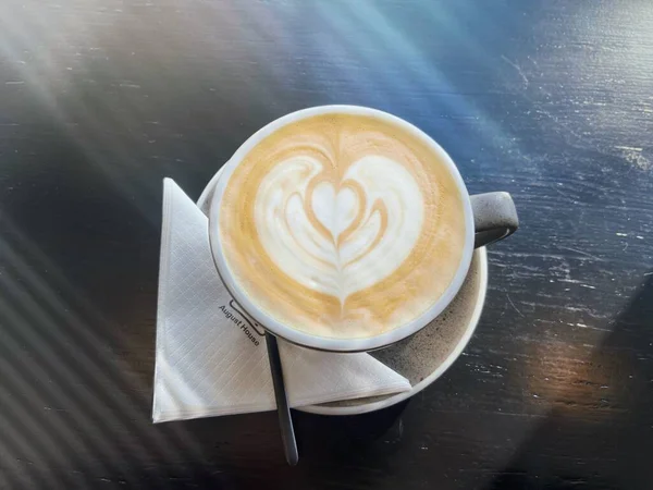 cup of cappuccino coffee with a heart on a wooden table