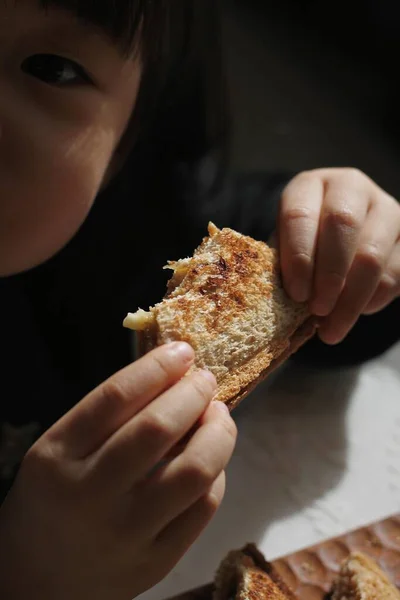 woman eating bread with a slice of cheese