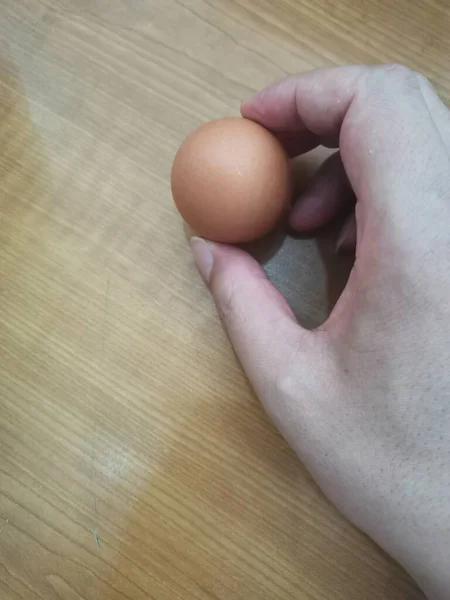 egg in hand on wooden background