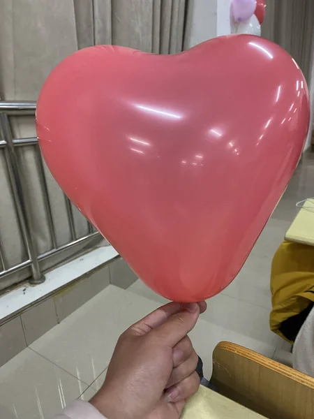 woman holding heart shaped balloon in hand